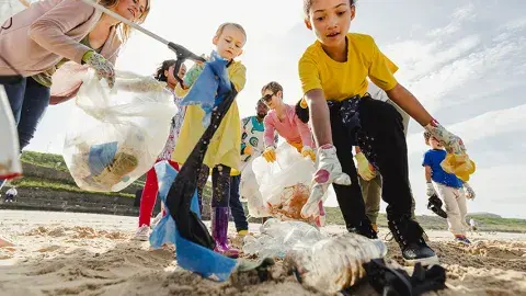 Kids and parents clean up trash from a beach