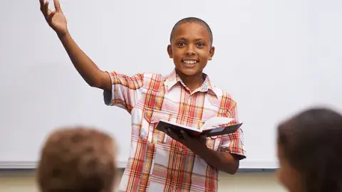 Young person speaking with enthusiasm in front of his classroom
