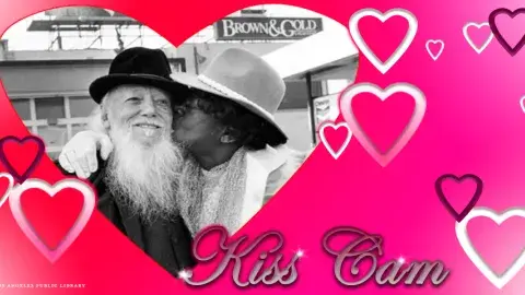Kiss cam hearts around a couple kissing
