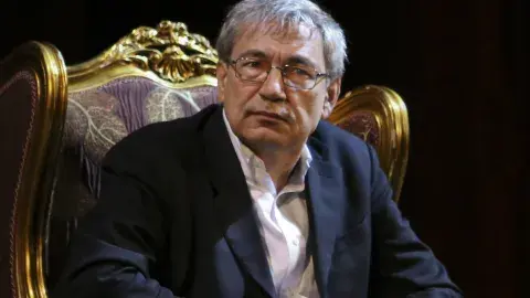 Orhan Pamuk sitting in a big gold chair