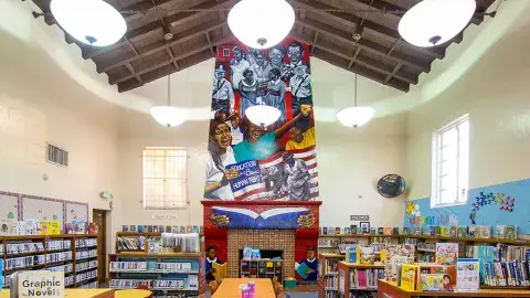 Interior of Angeles Mesa Branch Library with colorful mural called, Education is a Basic Right, over fireplace