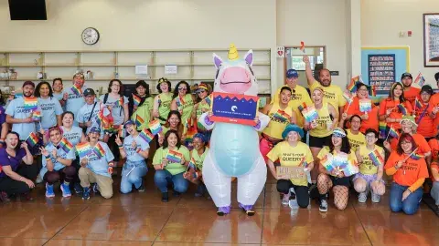 a person in a unicorn costume in front of a group wearing rainbow colored tshirts