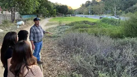 teens watching a gardner looking at native plants