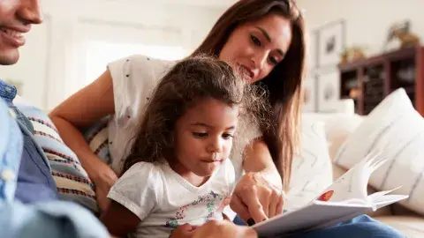 a Latinx family reads aloud together on the couch