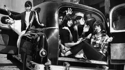 teenagers waving from inside a hearse