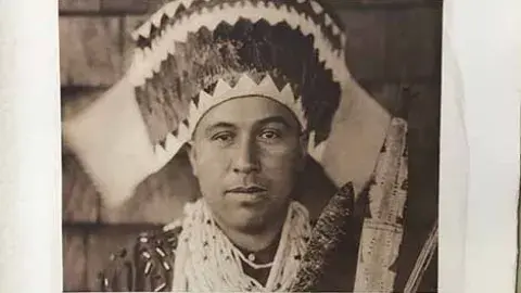 Plate 455 Tolowa Dancing Head-Dress.  Native American Tolowa man wearing a head dress, photographed looking straight into camera with plain expression
