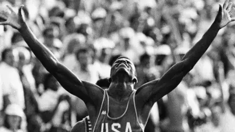 Carl Lewis raises his arms in victory at the LA 84 olympics