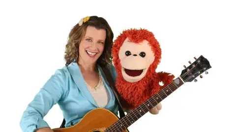 Alana holding a guitar and monkey puppet