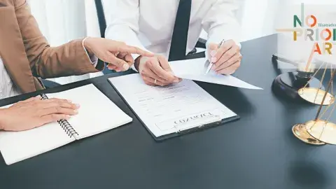 The hand of a person in a suit points to a document held by another person, next to a gavel and scales