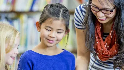 Two children listen to a STAR reader at the library.