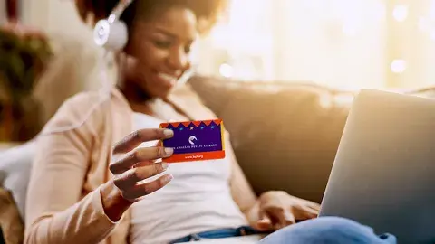 women holding her library card wearing headphones