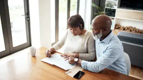 couple reads paperwork together at table