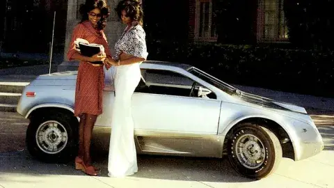 two people stand in front of small futuristic car