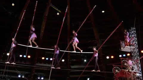 A color photo of acrobats on a tightrope
