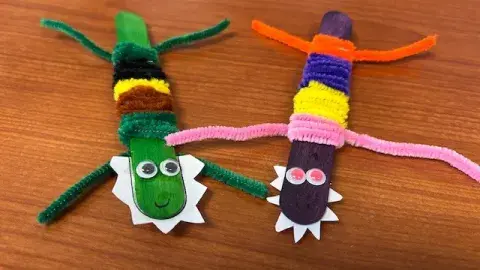Image is of two popsicles sticks covered by chenille stems that were used to create the body and legs of the alligators. 