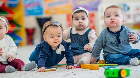 Babies crawl on the floor towards toys