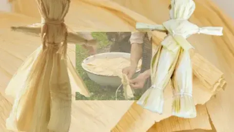 Two corn husk dolls in front of a wooden table 