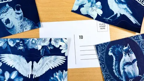 Four cyanotype printed postcard fronts scattered around the backside of a postcard.