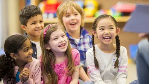 Children smiling at adult reading to them