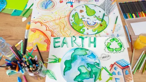 Wooden table with art supplies and drawings of planet earth