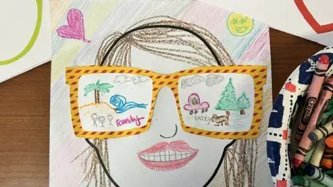 A colorful self-portrait with summer memories drawn onto the lenses of yellow with red striped glasses.
