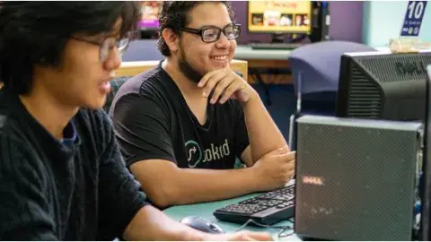 Two teenage boys working on a computer