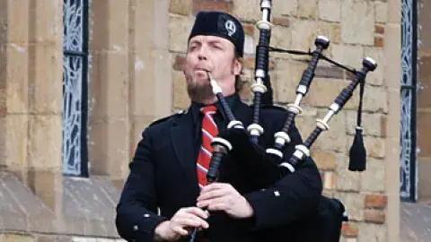 John McLean Allan playing his bagpipe in front of a church