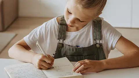 A young girl writing in a journal.