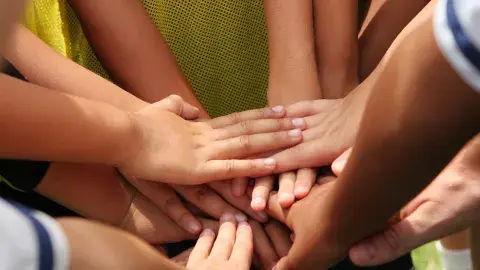 kids hands together in a group huddle