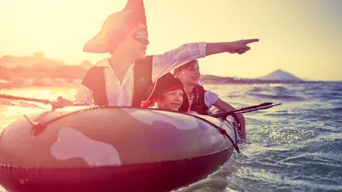 kids dressed as pirates on a rubber boat on water
