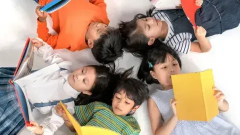 Kids reading books lying in a circle on the ground