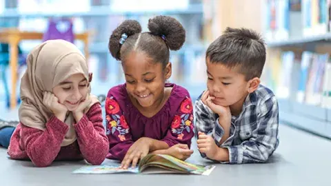 three kids reading a book together