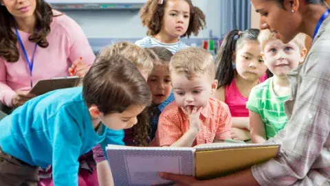 children looking at a book being read