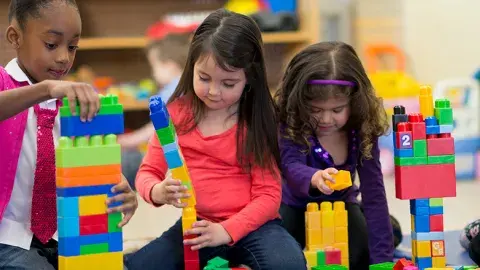 Three girls build with Lego blocks