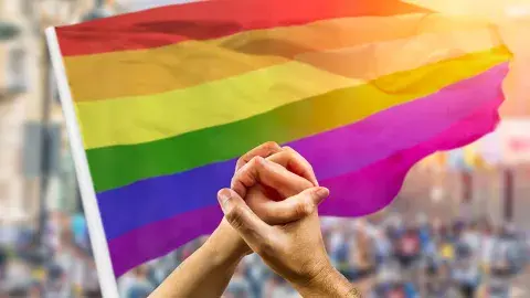 lgbtqia flag and hands intertwined
