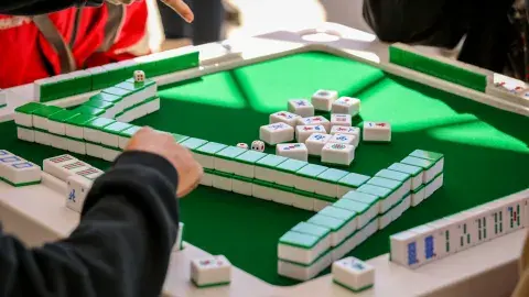 Mah Jongg table with hands playing game. 