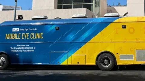 Mobile Eye Clinic bus parked in front of library.