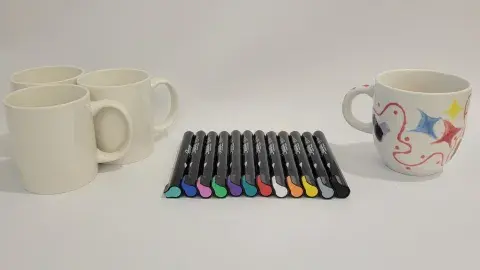 Mugs and paint pens laying on a table