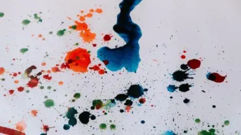 Different colors of paint splashed onto white paper