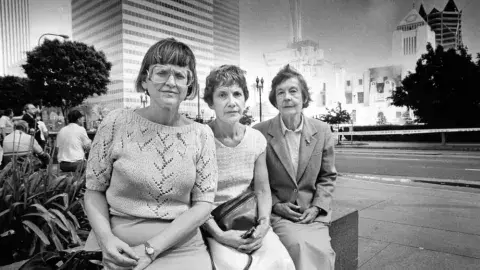 Three librarians are pictured in front of the burning Central Library 