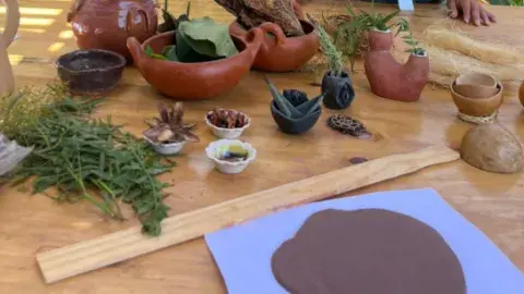 Clay is spread out on a table, along with dried flower petals and other textures that can be added to the clay