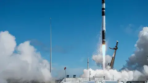 rocket blasting off with smoke and a blue sky