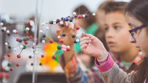 Several children are looking at a 3D model of atoms. 