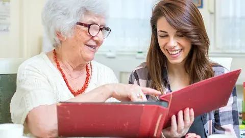 teen helping a senior look at a photo album