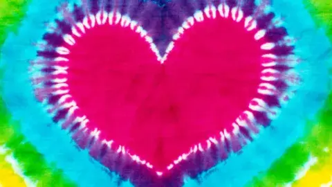 A tie-dye of a pink heart surrounded by the colors of the rainbow.