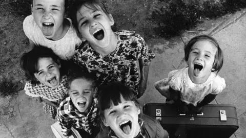 historic photo of children looking up with tongues sticking out