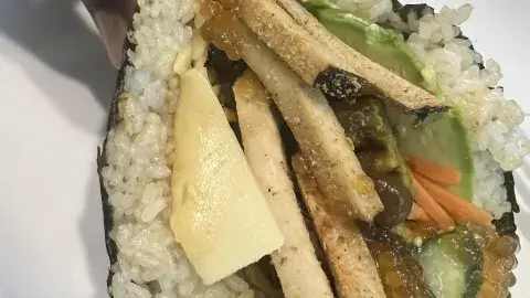 Vegan sushi taco being held over a white plate.