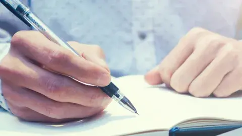 hands writing in notebook