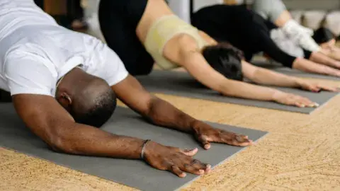 People in row doing child pose on yoga mats