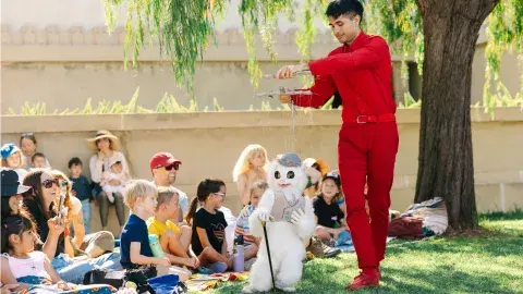 Man with marionette with a crowd of kids.  